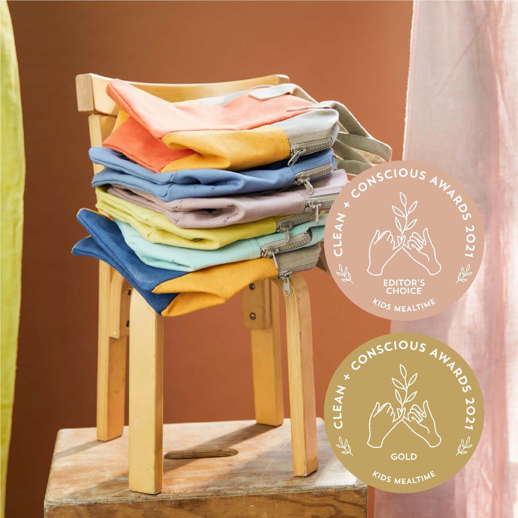 a chair with colorful Cotton sustainable lunch bags by fluf with the logo of the CLEAN + CONSCIOUS AWARDS 2021. Gold one and the editor's choice