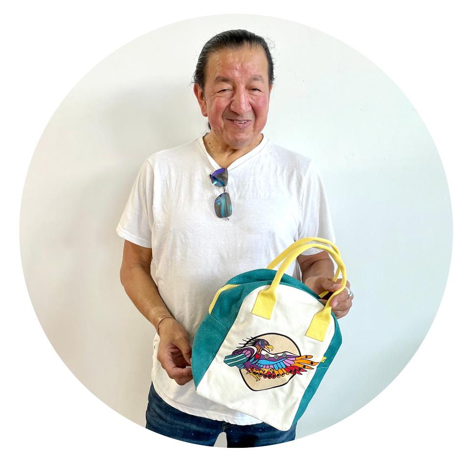 Philip Cote, designer, Indigenous Artist, Activist, Educator, Historian and Ancestral Knowledge Keeper holding Lunch bag featuring Indigenous art and symbolism: wolf and eagle 